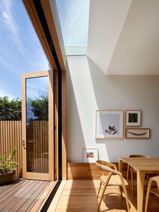 A skylight above a dining table, with a glazed door opening to a deck and timber screen fence.