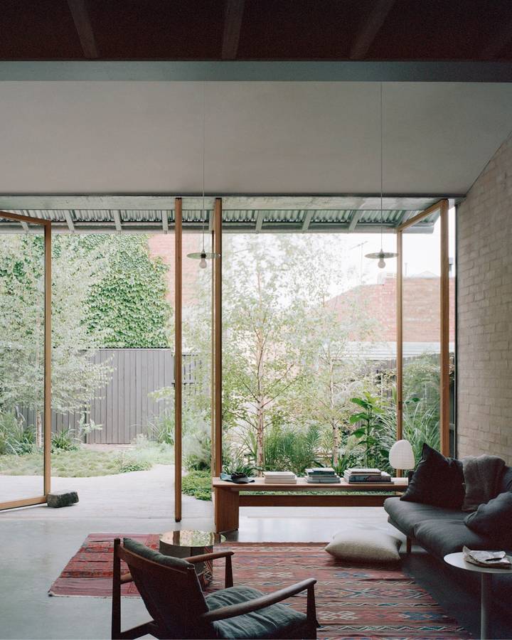 A living room with a corrugated roof and a glazed wall looking to a garden, with a low window seat.