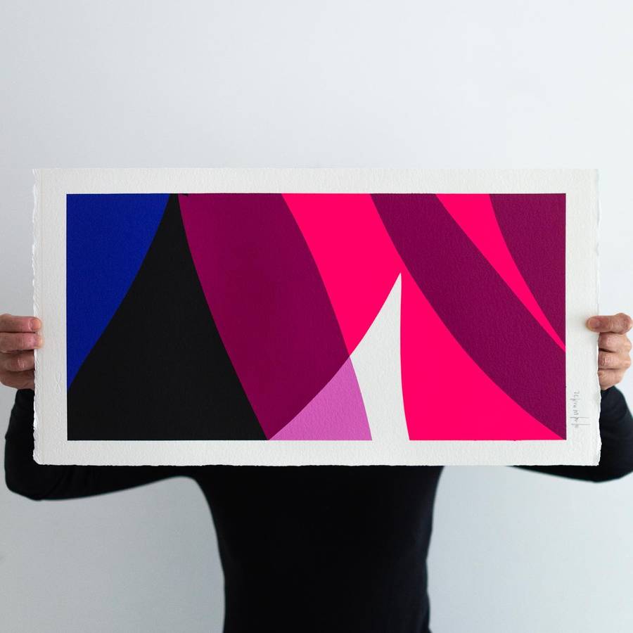 A person holding a landscape sheet of paper painted with blue, black, magenta and pink curved forms.