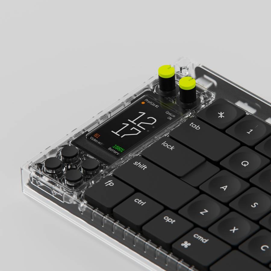 A close view of a mechanical keyboard with a clear case, black keycaps, two yellow green knobs and a small screen showing the time and battery level.