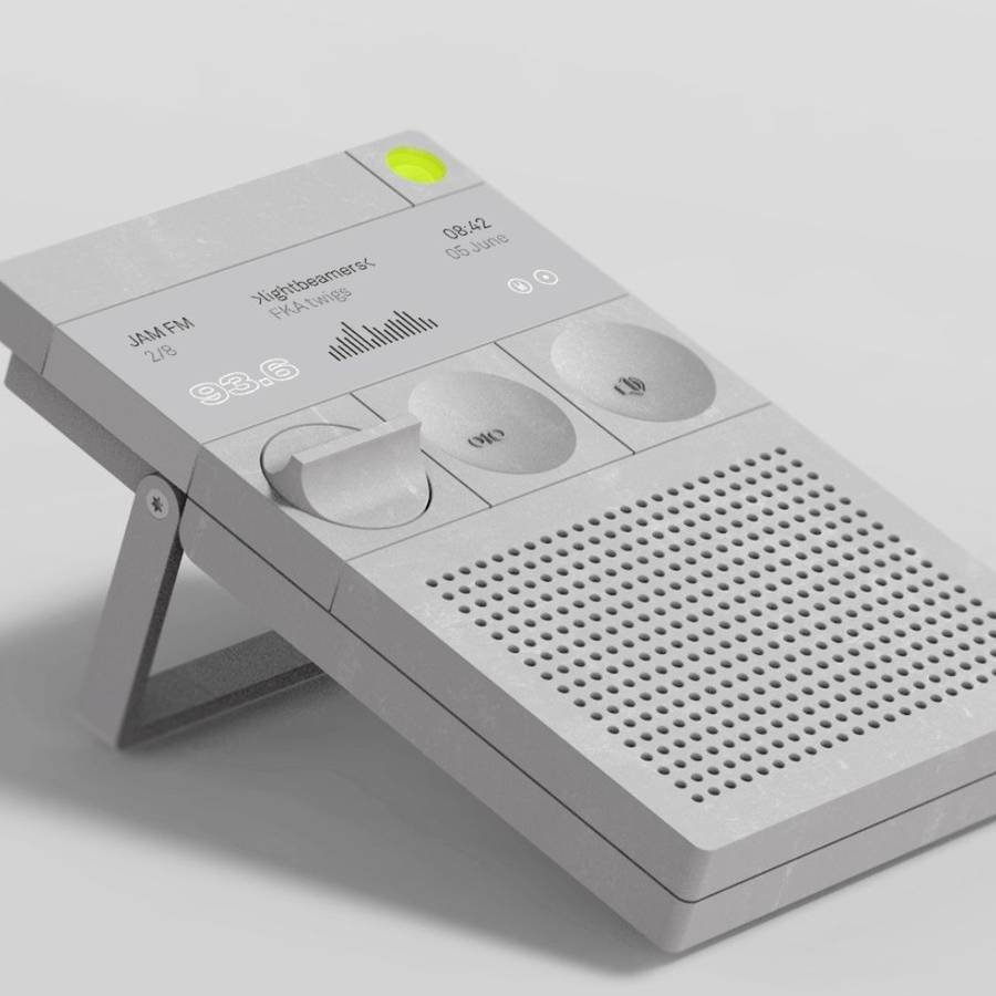 A grey desk radio on a fold out stand, with a perforated speaker grille, two oval controls, a green button and a display reading 93.6.