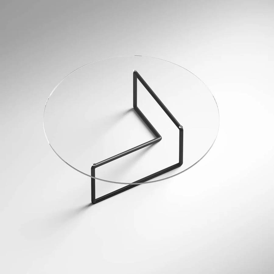A round glass topped coffee table on a folded black metal rod base, on a pale grey ground.