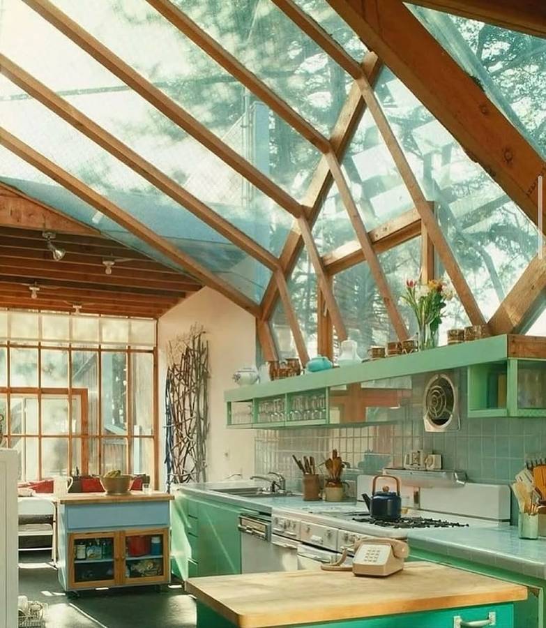 A kitchen under a glazed timber framed gable roof, with mint green cabinets and a tiled splashback.